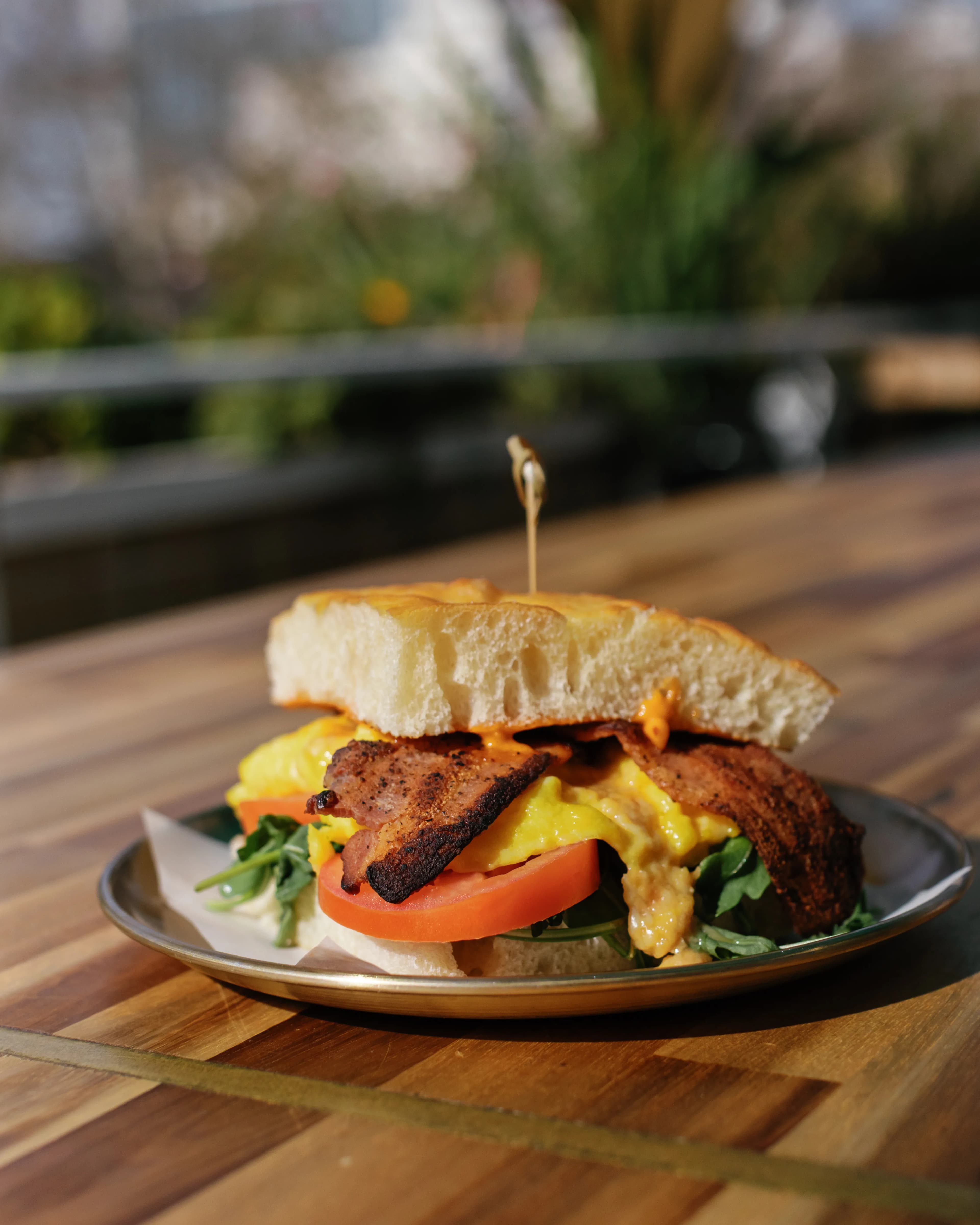 Breakfast sandwich with spiced meat patty, scrambled eggs, tomato and arugula on focaccia at Darling Aviary weekend rooftop brunch in Downtown Sacramento
