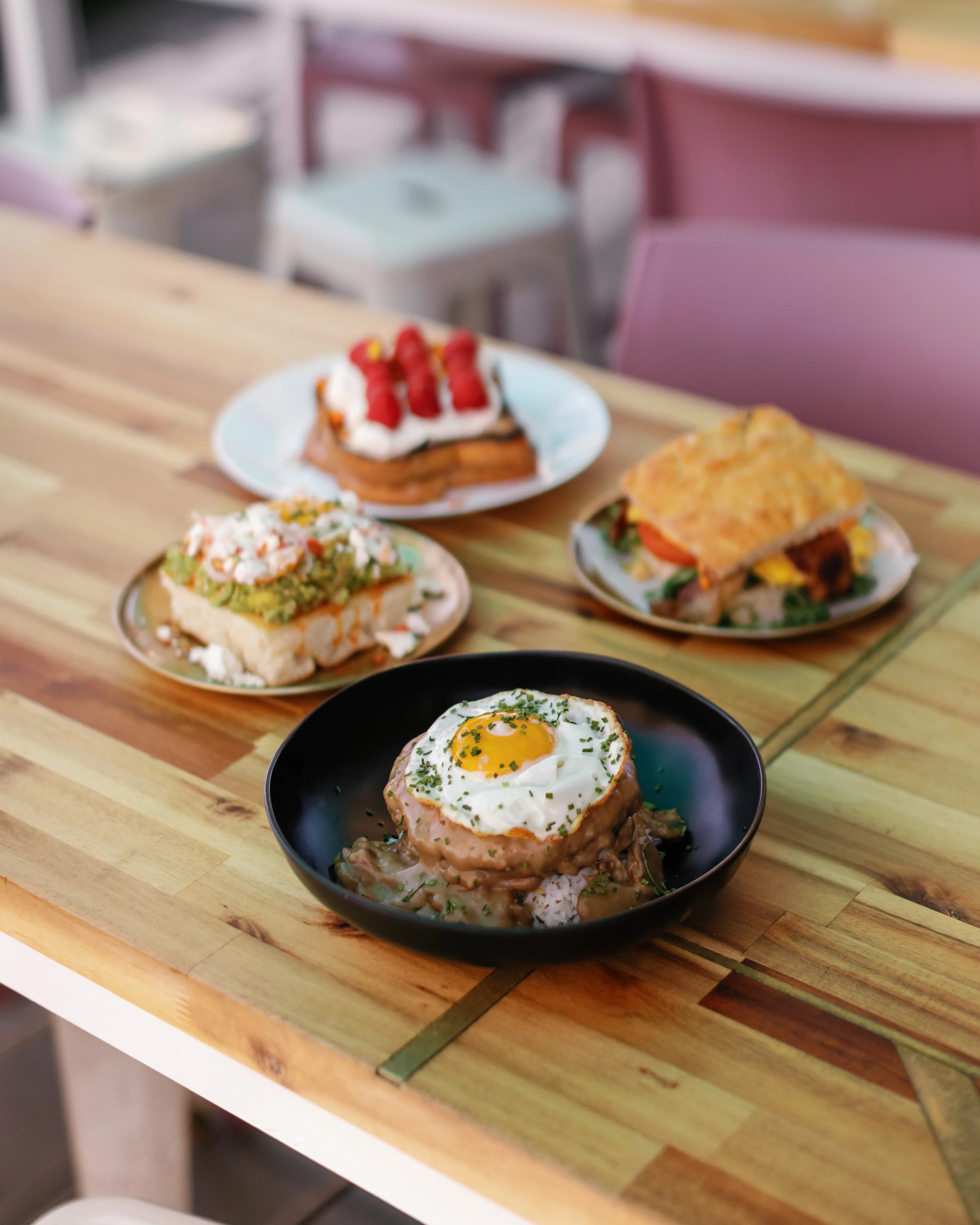 Overhead weekend brunch spread with loco moco, avocado toast, French toast and a breakfast sandwich at Darling Aviary rooftop in DoCo, Downtown Sacramento