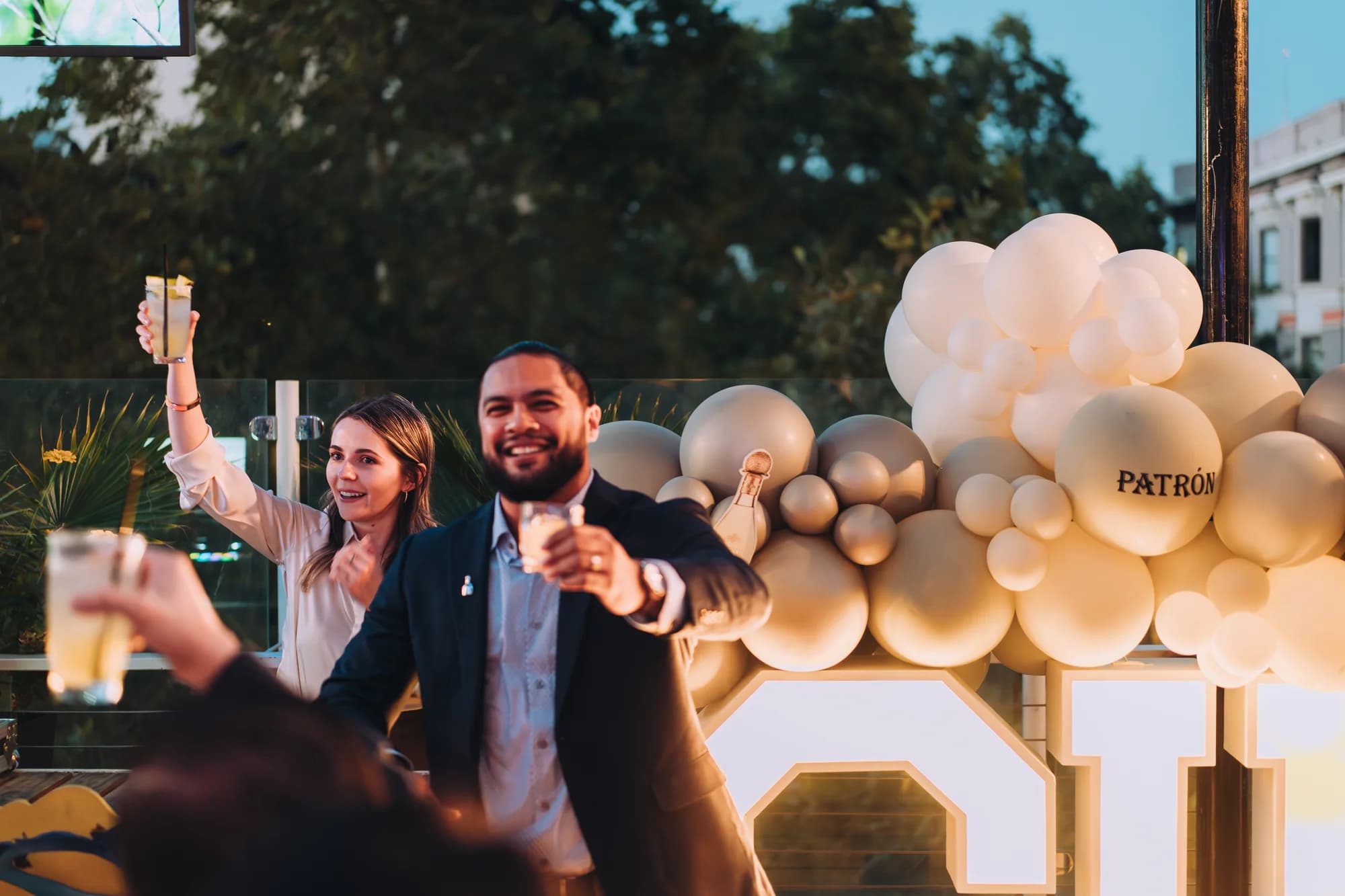 Guests raising glasses in a toast at a private rooftop event at Darling Aviary with string lights and the K Street skyline in Downtown Sacramento