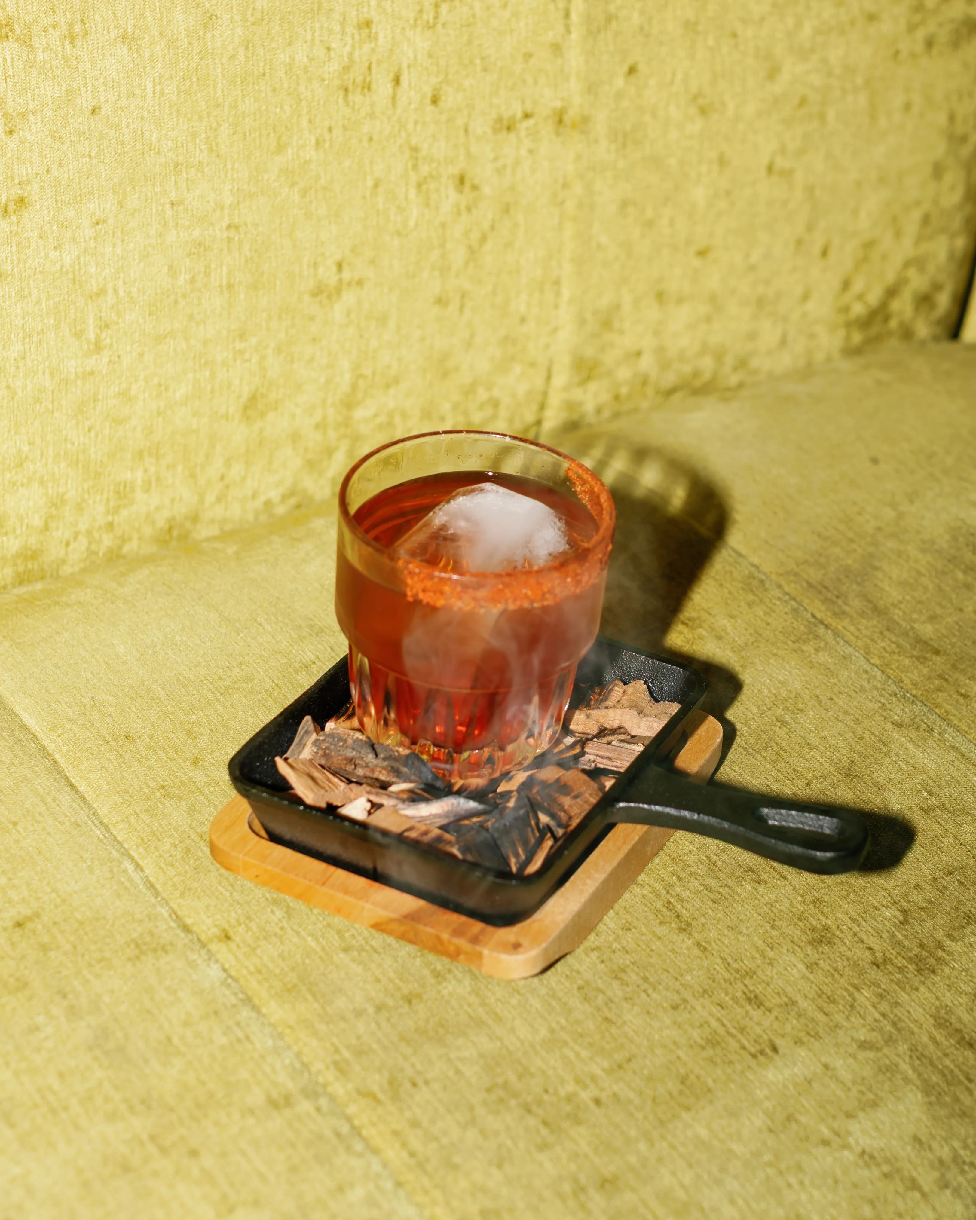 Smoked Old Fashioned cocktail in a rocks glass on a cast iron skillet with a smoke dome at Darling Aviary rooftop bar in DoCo, Downtown Sacramento