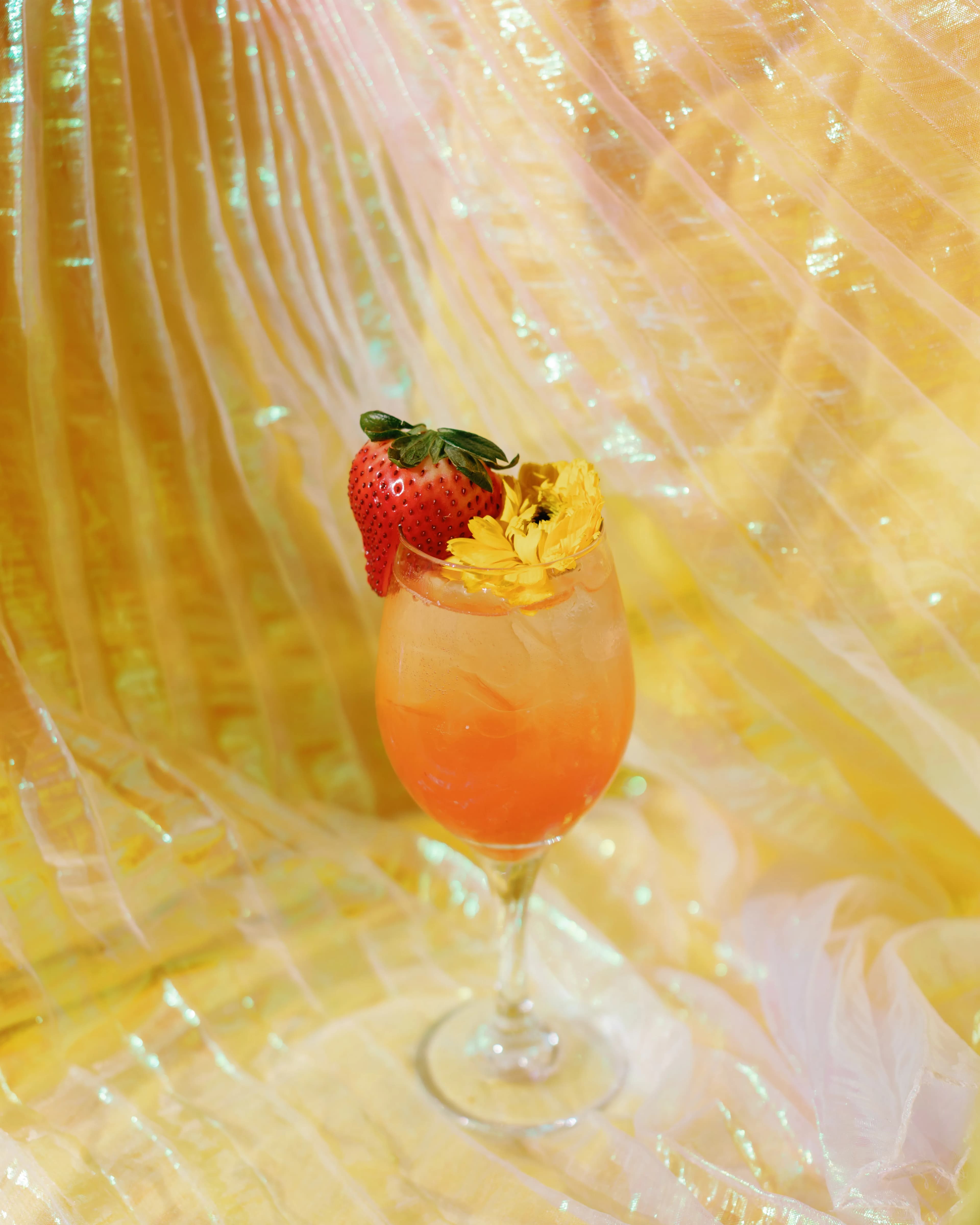 Strawberry Blossom signature cocktail with peach to orange gradient, fresh strawberry and edible flower at Darling Aviary rooftop bar, Downtown Sacramento