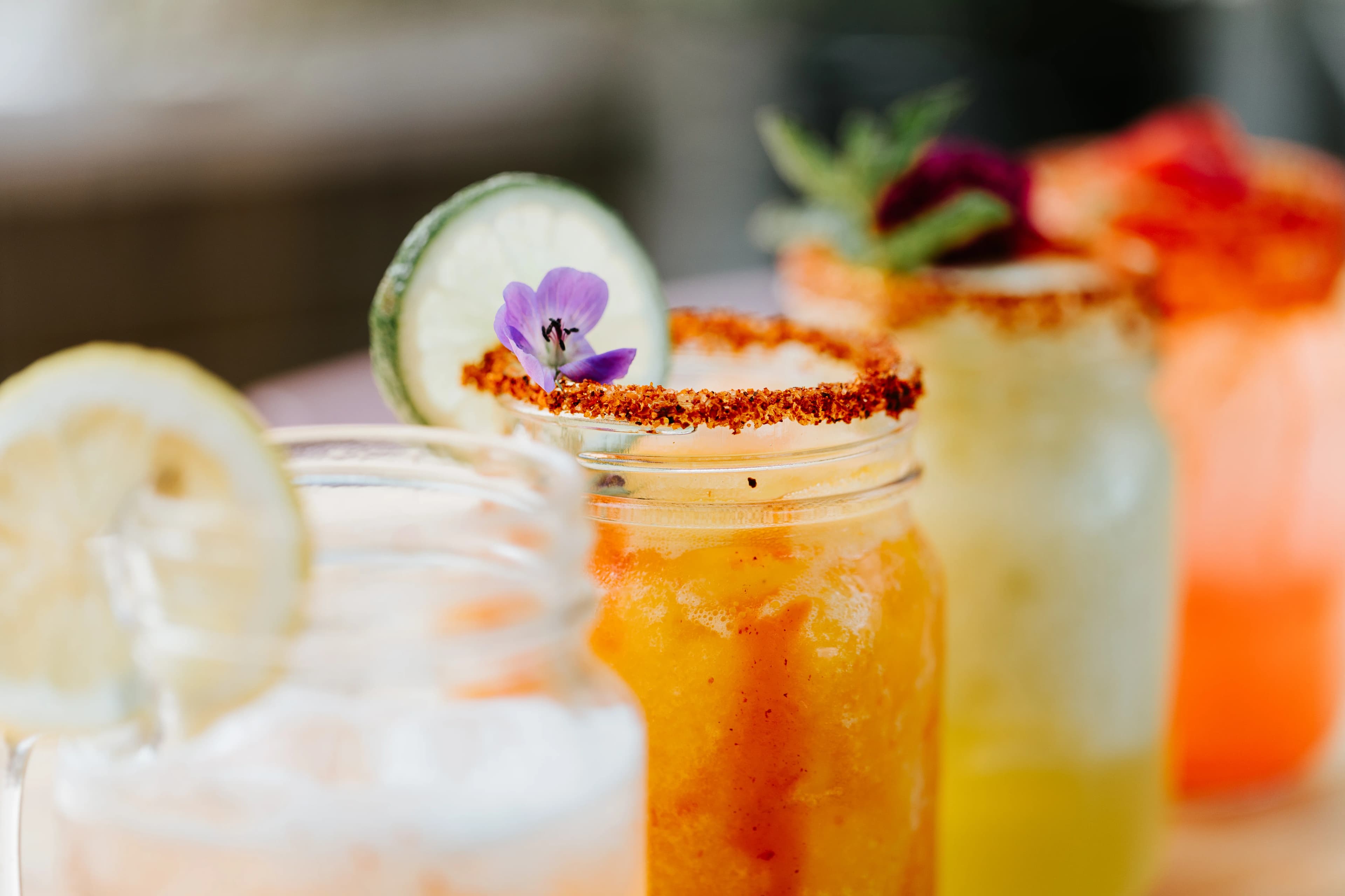 A variety of colorful craft cocktails lined up on the bar at Darling Aviary rooftop bar in Downtown Sacramento
